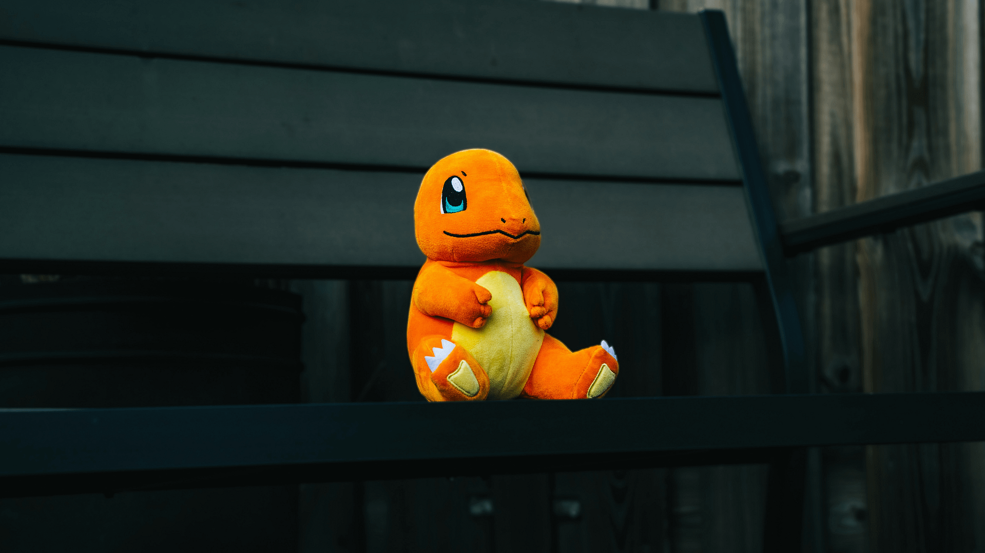 A plush toy of Charmander, one of the most iconic Pokémon, sitting on a dark wooden bench. Symbolizing digital collectibles, AR gamification, and the psychology of collection that makes Pokémon Go such an addictive digital experience.